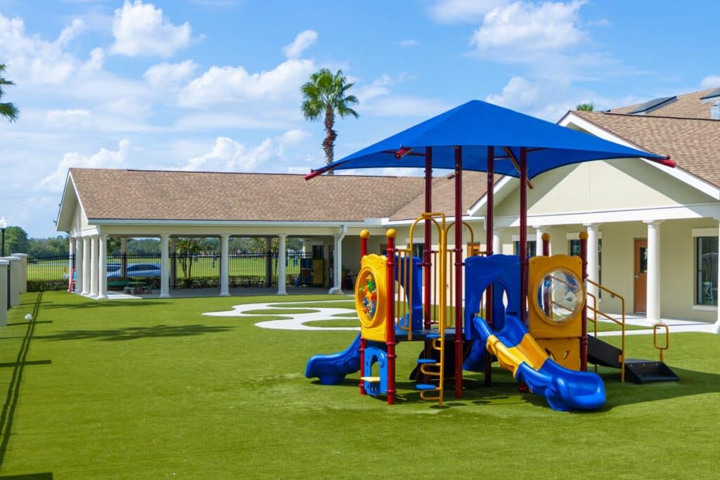 An outdoor play set in a playground at a preschool or daycare stands empty.
